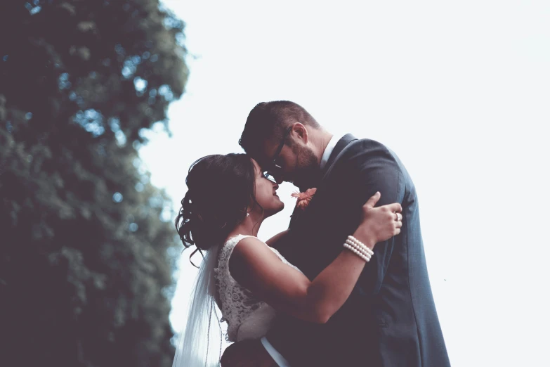 a bride and groom kissing on the cheek