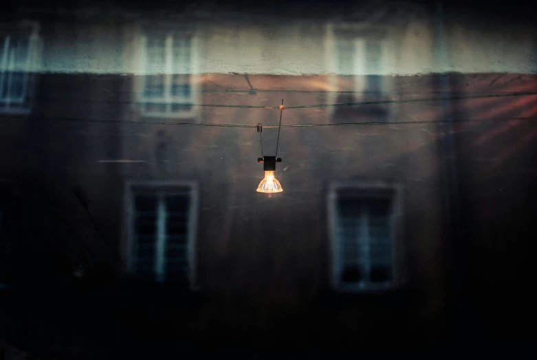 a light bulb hanging from a wire next to two windows