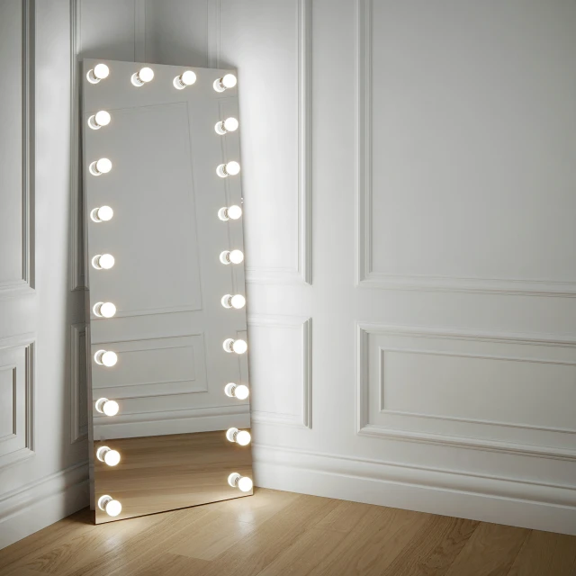 the large illuminated mirror is next to a wooden floor