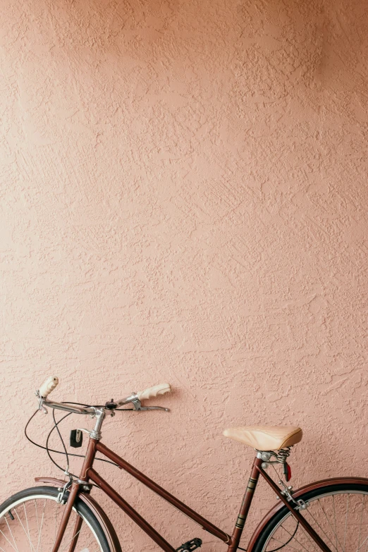 a bike is parked against a wall with its basket hanging off the front wheel