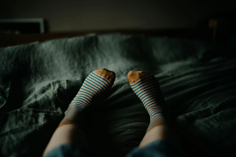 a person with a pair of socks on, resting on a bed