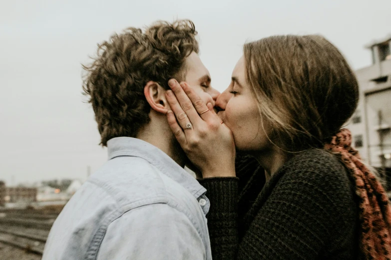 a woman is kissing a man while he's looking at her face