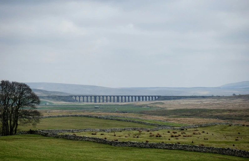 large stone walls by a lonely field with bridge