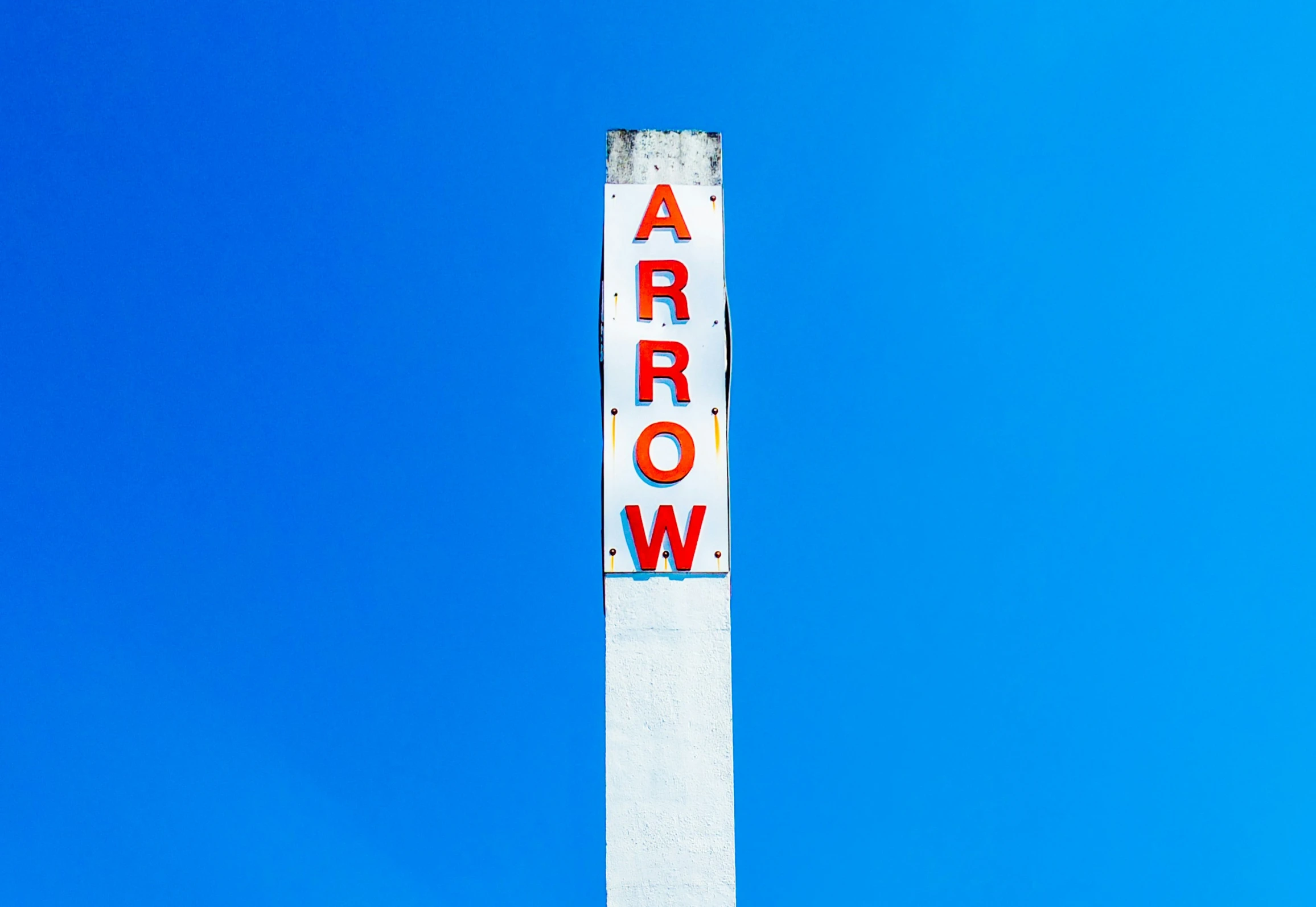 an arrow sign in the sky under a blue sky