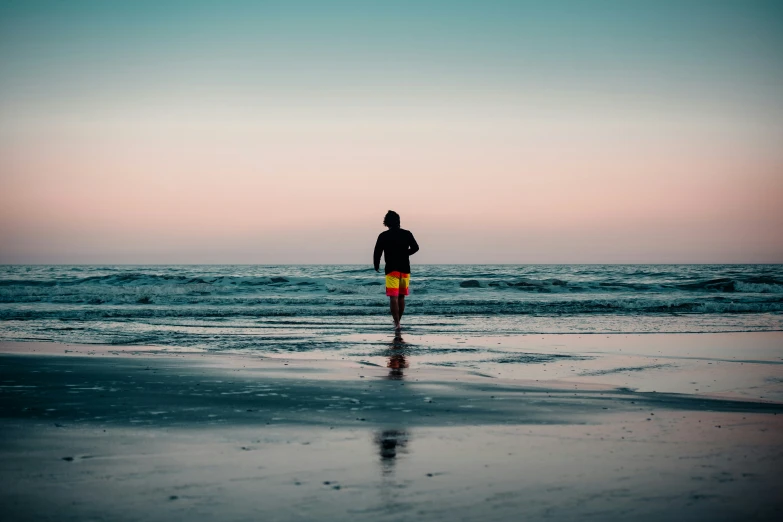 a man standing in the surf on top of a beach