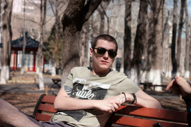 a man in sunglasses is sitting on a bench