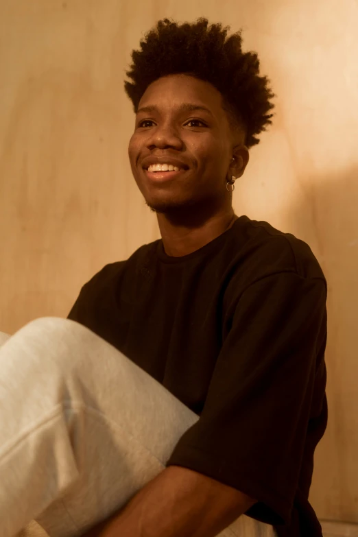 a young person wearing ear buds smiles and sits