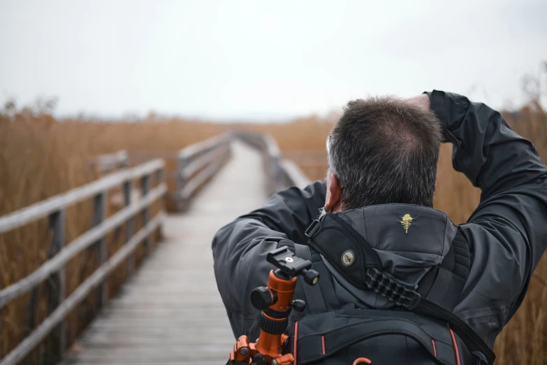 a man walking across a bridge carrying a small black backpack