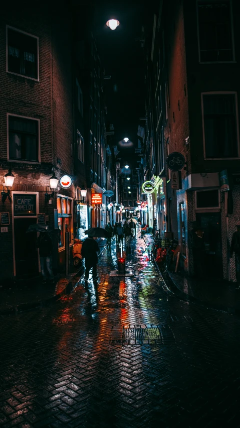 a street scene at night with a person walking down the sidewalk