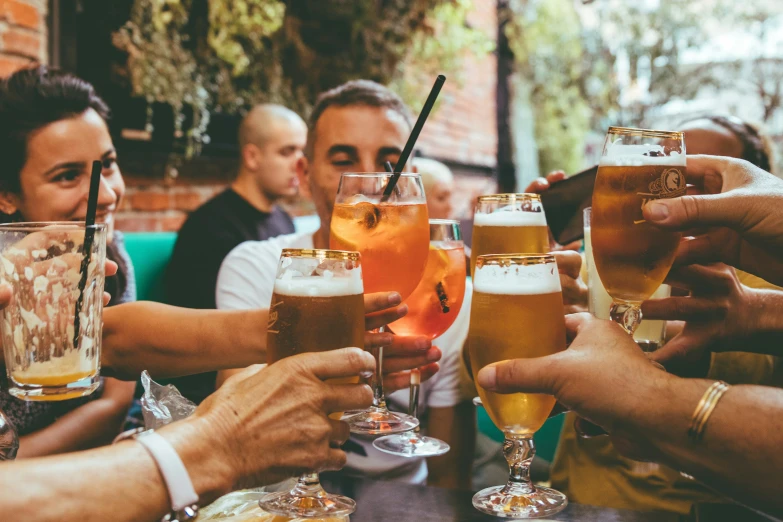 people sitting at a table holding glasses of alcohol and posing for a camera