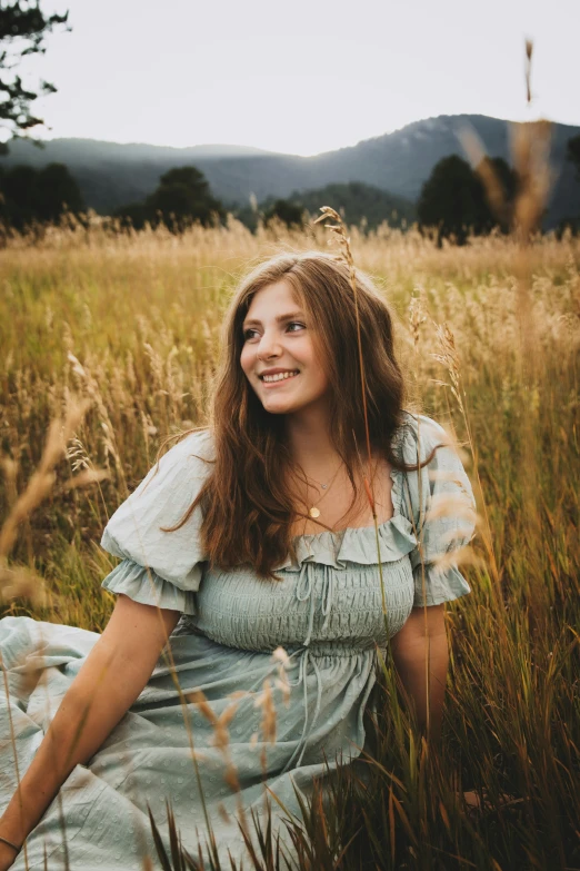 a smiling young woman sitting in the grass