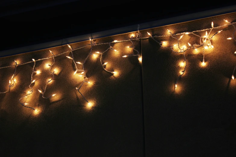 lighted lights are hanging on a wall with black background