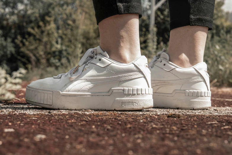 a person's foot wearing white shoes and jeans