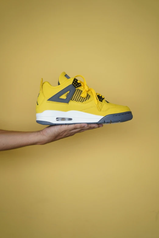 a hand holding up a yellow jordan basketball shoe