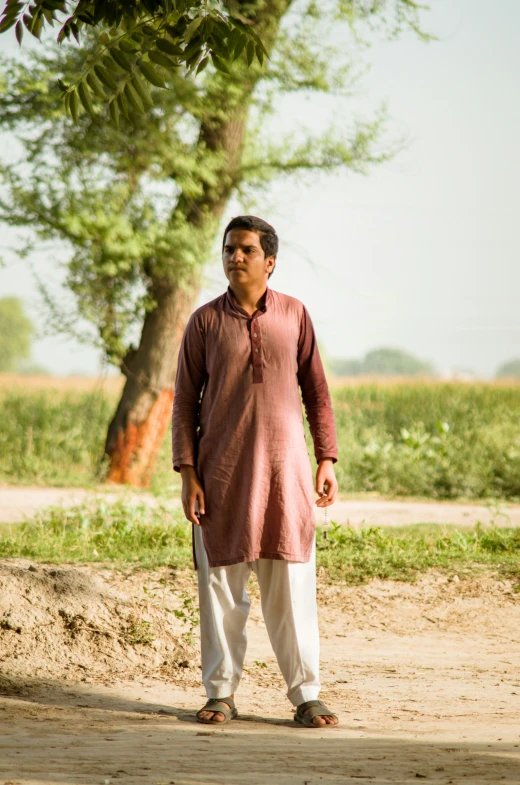 a man wearing an unoned red shirt standing under a tree