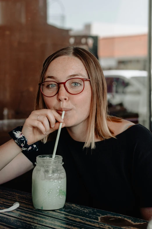 a woman sitting at a table with a drink in front of her