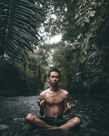 a man meditating in the jungle with  on
