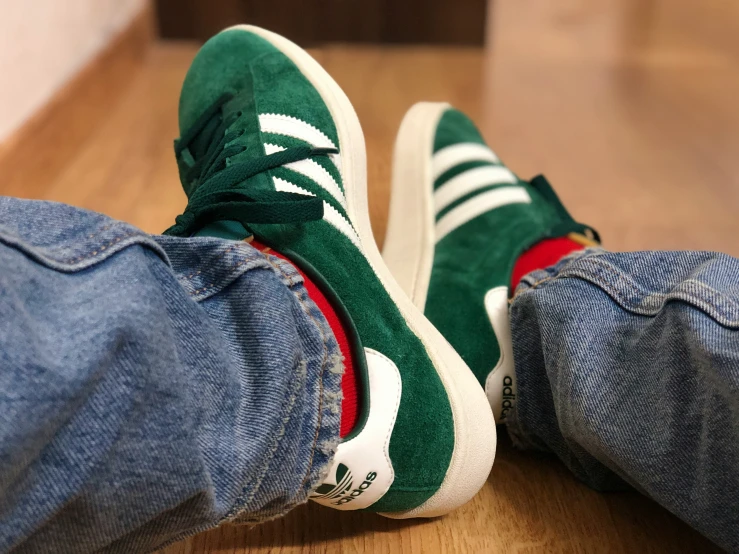 pair of green adidas shoes sitting on wooden floor