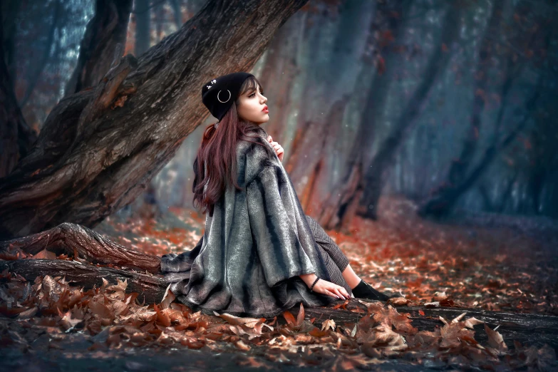 a woman sitting under a tree surrounded by leaves