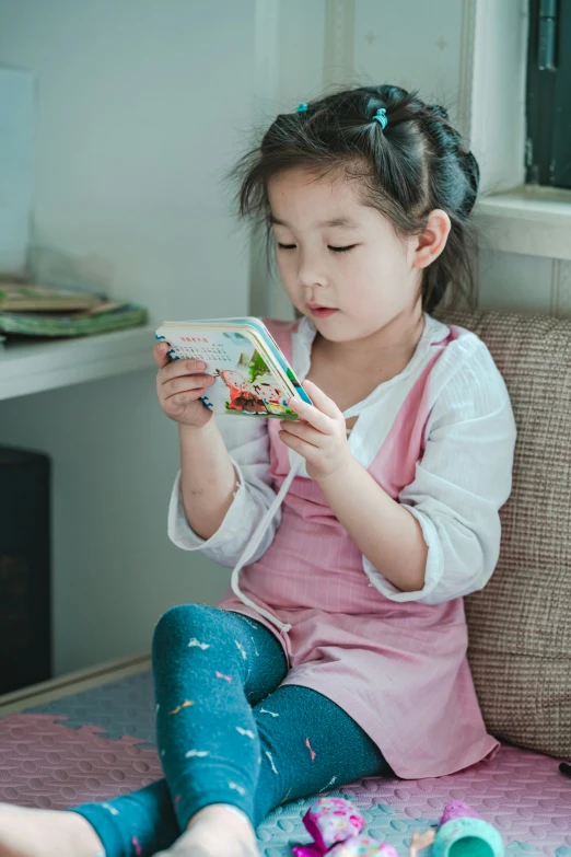 a girl sitting on a chair reading a book