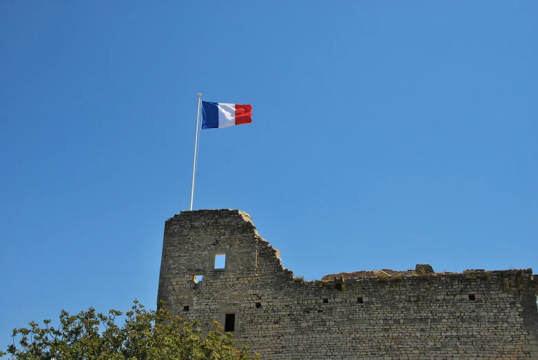 the flag of france flying above an old castle