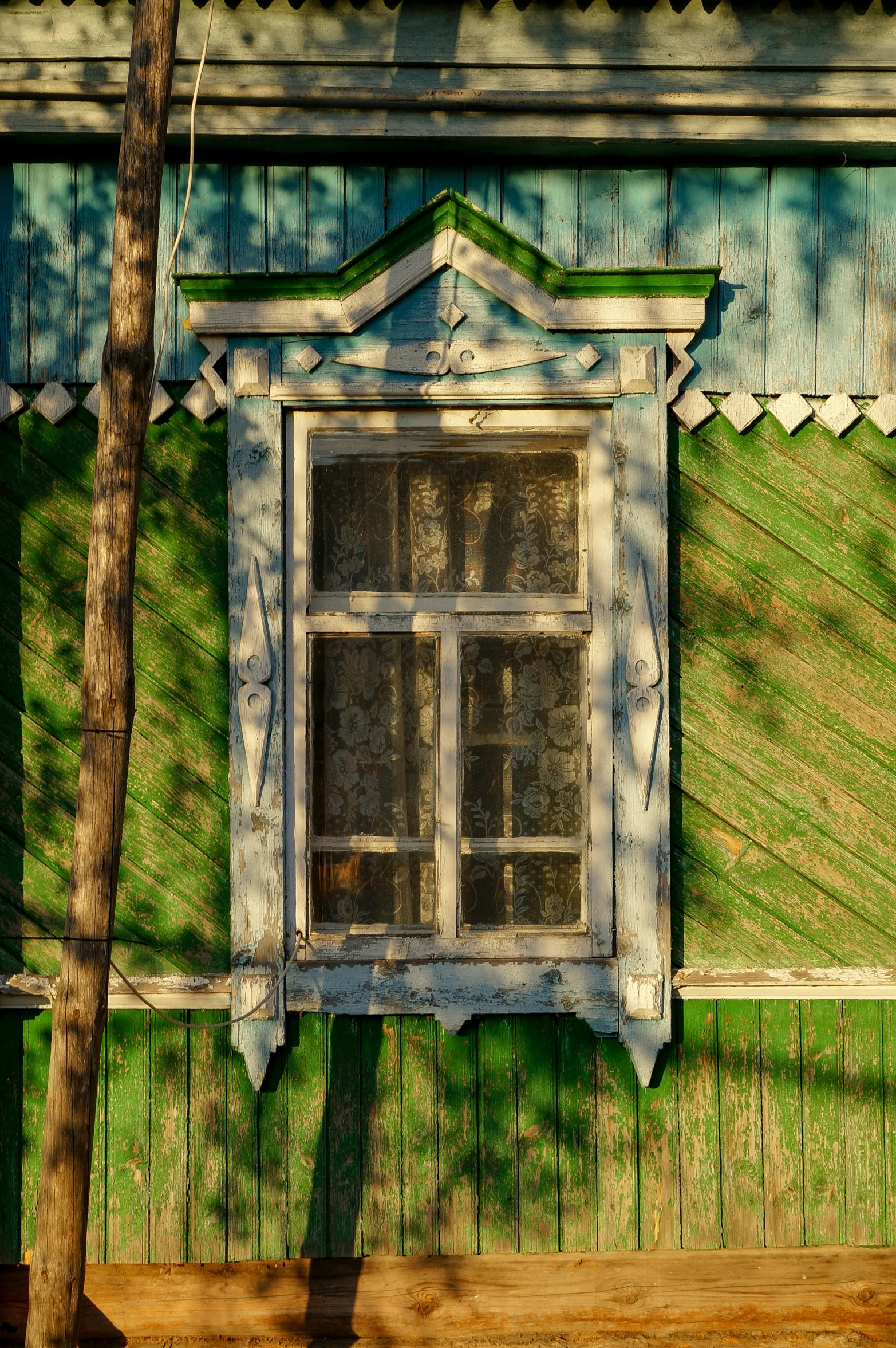 a window with a green roof is near a tree