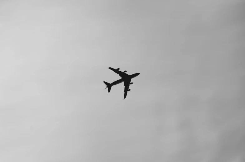 an airplane flying against a cloudy grey sky