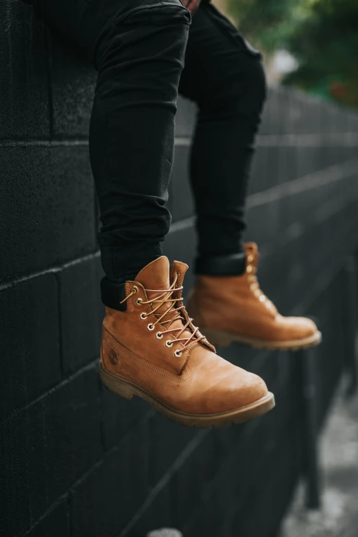 a man sitting on the ledge of a building, wearing brown shoes