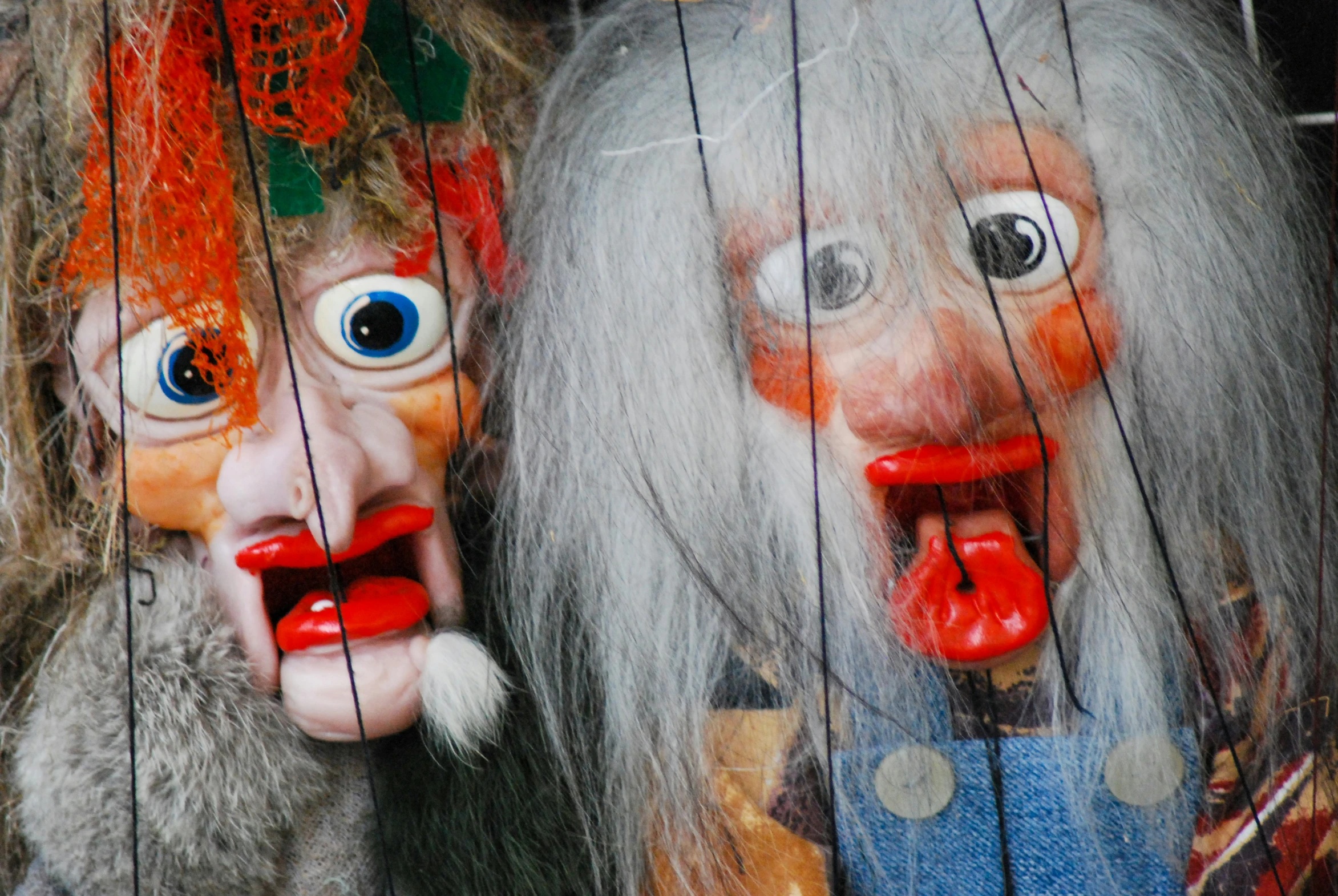 puppets of two trolls hanging from wires on display