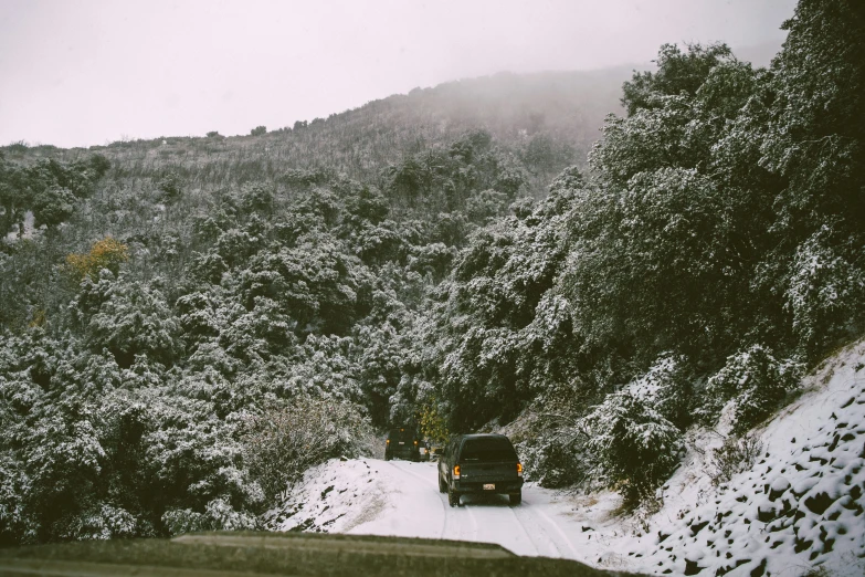 several vehicles are traveling down a snow covered mountain road