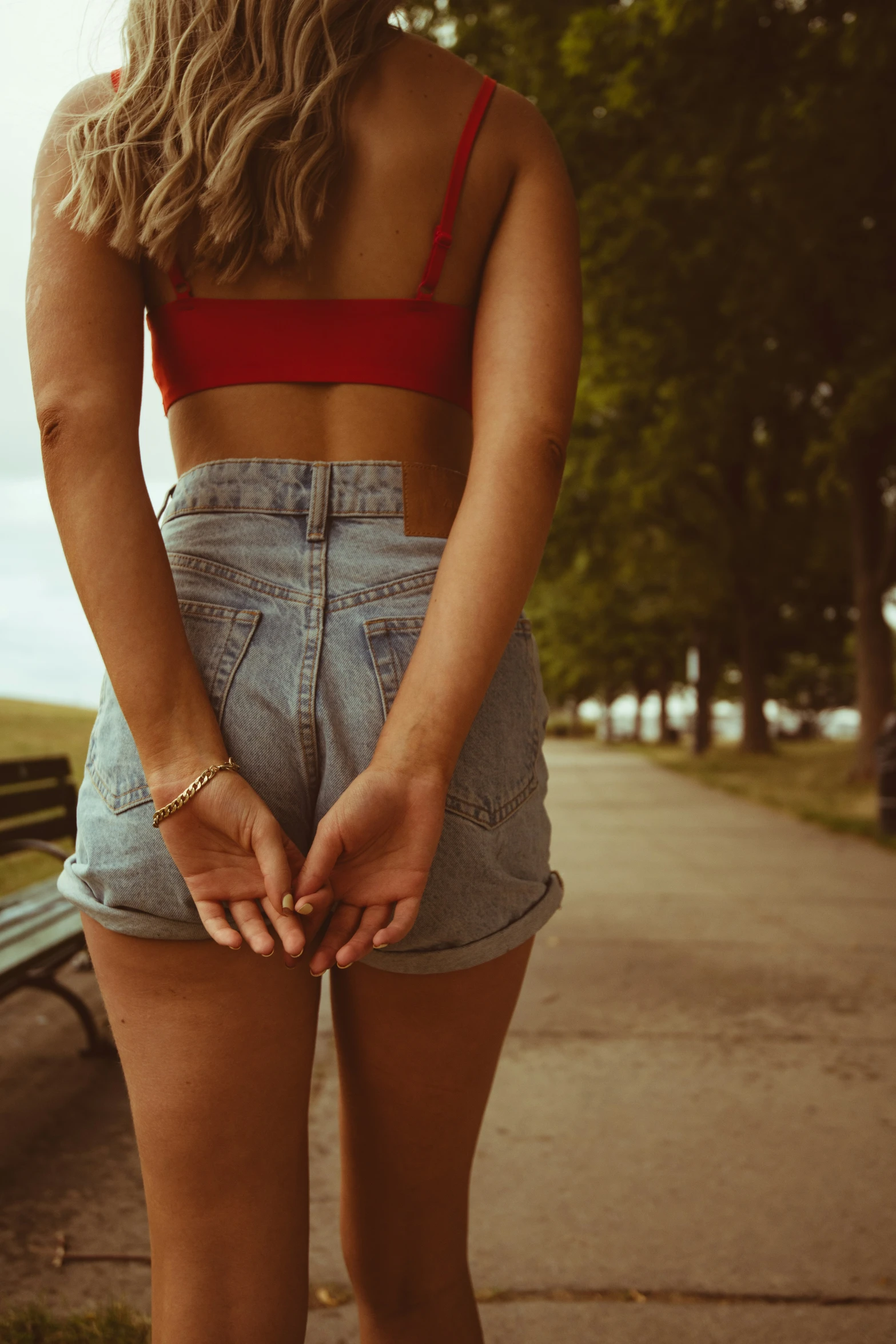 a woman in a red crop top and high waisted shorts standing on a sidewalk