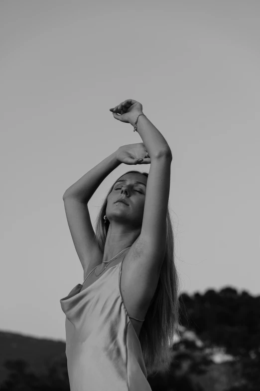 a woman reaching up to the sky while wearing a dress