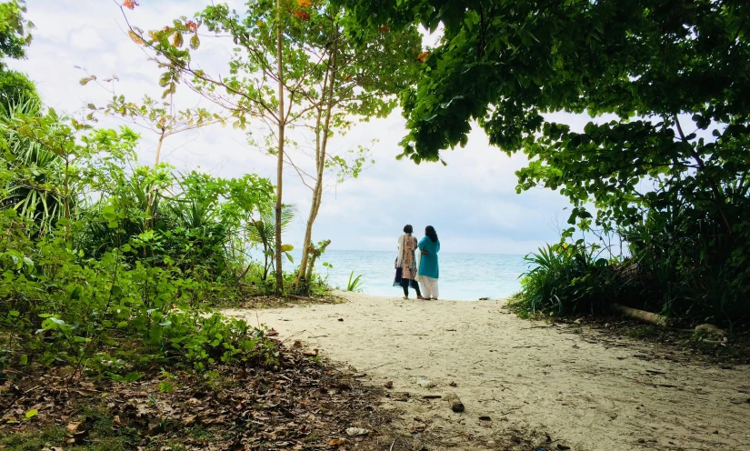 two people standing on a path near the ocean