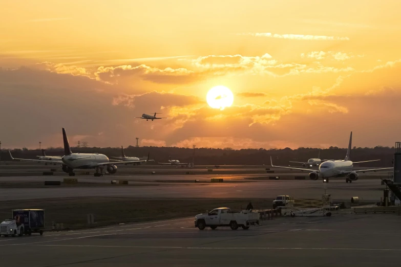 the sun sets over an airport as planes sit on the tarmac