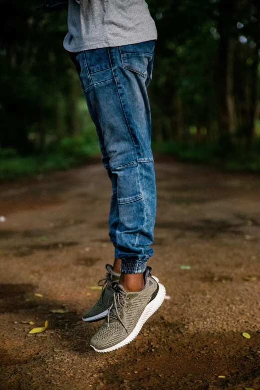 a man's shoes and legs stand in the middle of a path