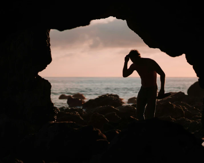 the person is standing at the entrance to the cave