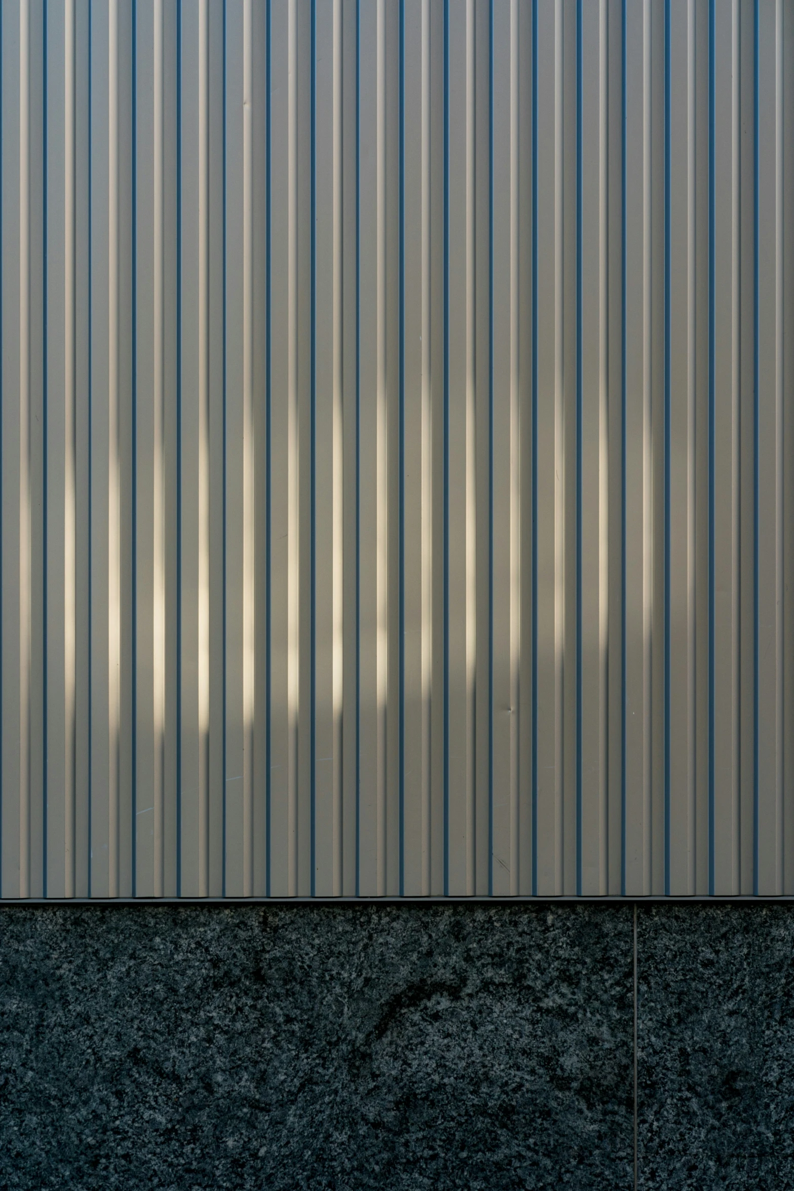 a gray concrete wall with a building in the back ground