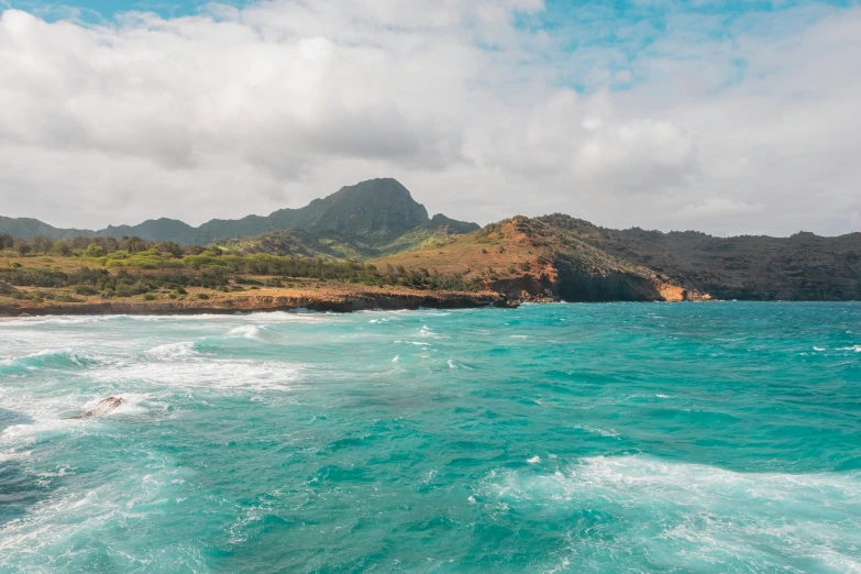 waves crashing in front of some large mountain ranges