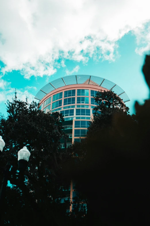 a large building behind some trees and clouds