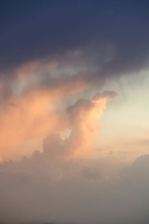 a cloud in the sky over a grassy field