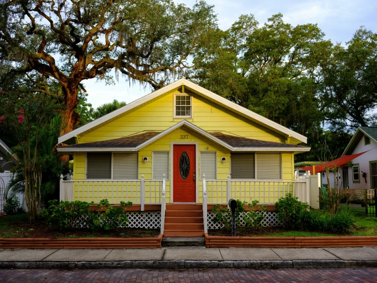 a yellow house sits in front of some trees