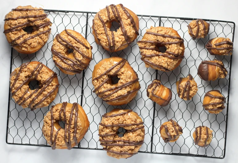 an array of glazed donuts sit on a cooling rack