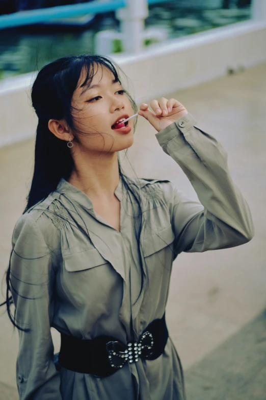 a woman in a dress holds an object in her mouth