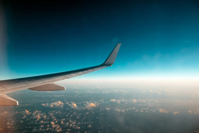 an airplane wing in flight high up in the sky