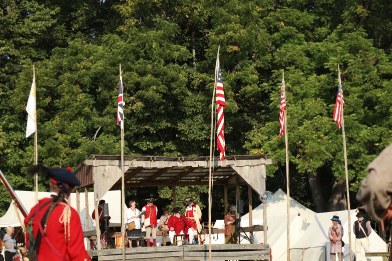 men in uniform stand near flags on the ground and watch