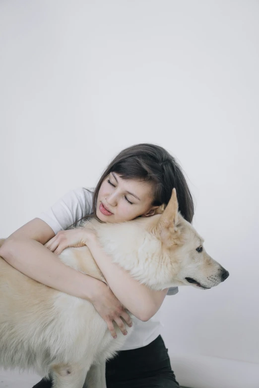 a woman sitting on the floor while hugging her dog