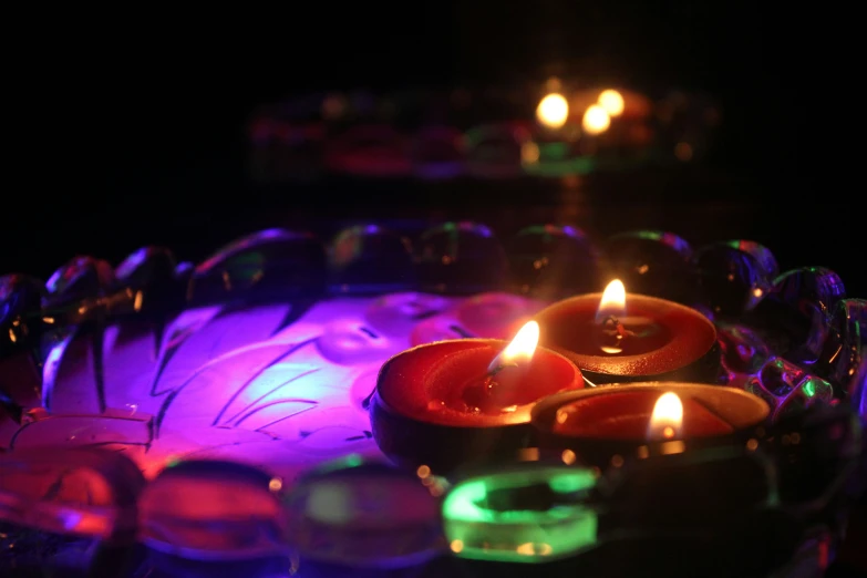 three lit candles with several bright lights and circular plate