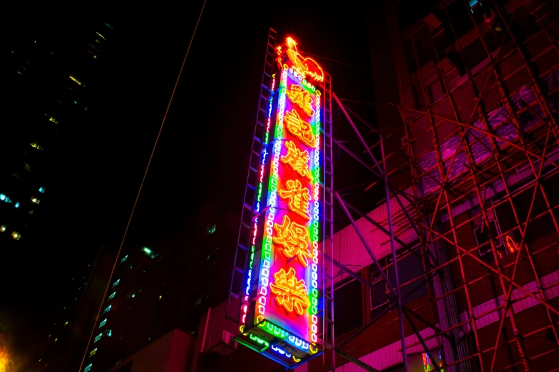a neon sign sitting on the side of a tall building