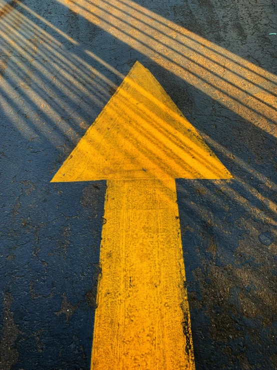 a yellow arrow painted on the ground and street markings