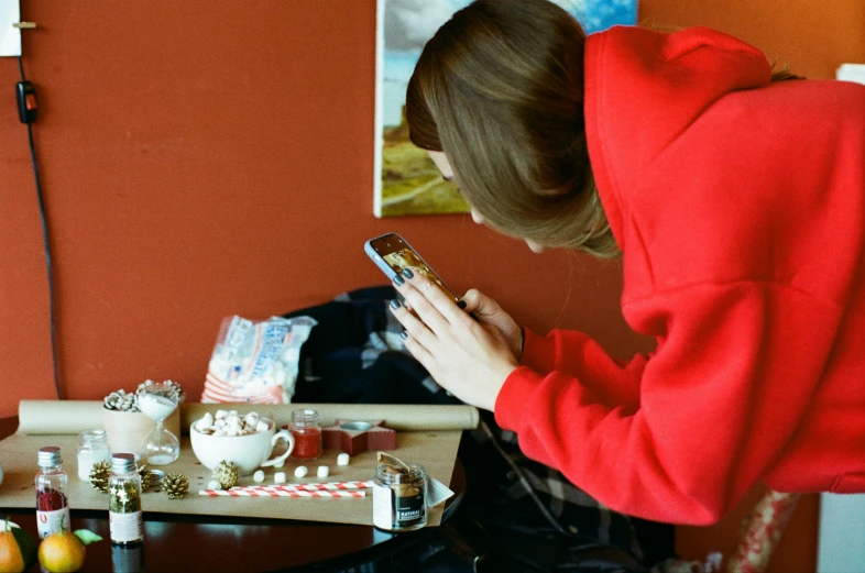 a girl in a red sweatshirt checking her cellphone